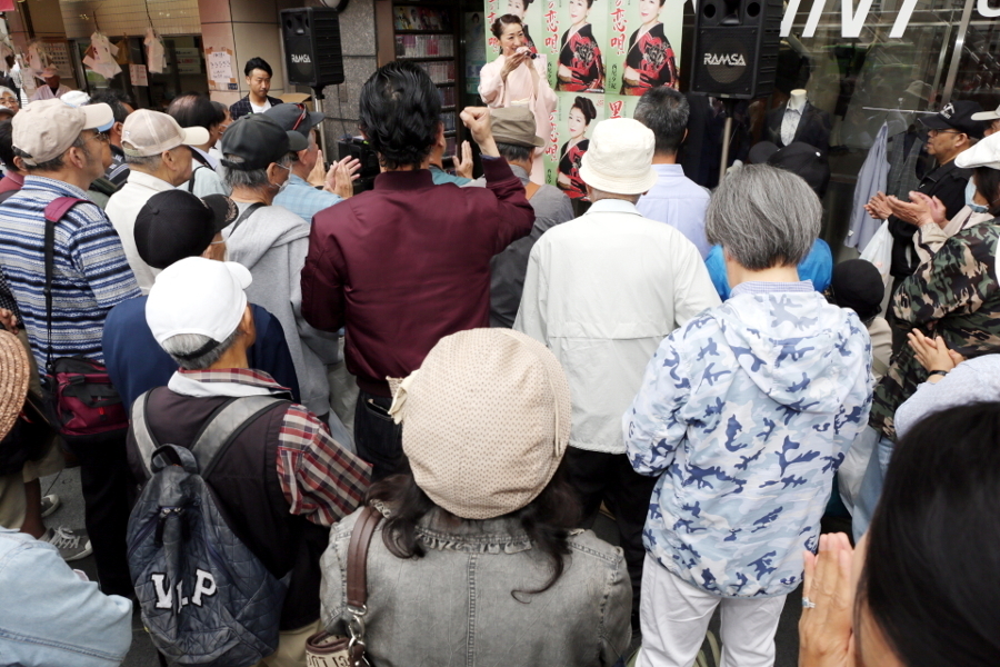 ミニライブが始まった。拳をあげる人、手拍子する人。前方には歌手のファンが。後方にはキャンペーン自体を楽しみに駆けつける人もいる（撮影：志和浩司）