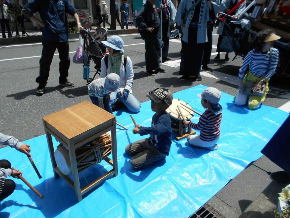 [写真]会場で太鼓をたたいて喜ぶ子どもたち