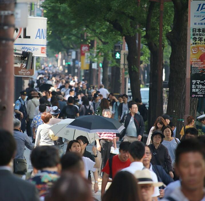 [写真]ビルの影がかかる御堂筋・西側の歩道は日差しを避け多くの人が歩いていた。大阪市では最高気温29.6度を観測した=20日午後3時すぎ、大阪市中央区で（撮影：柳曽文隆）