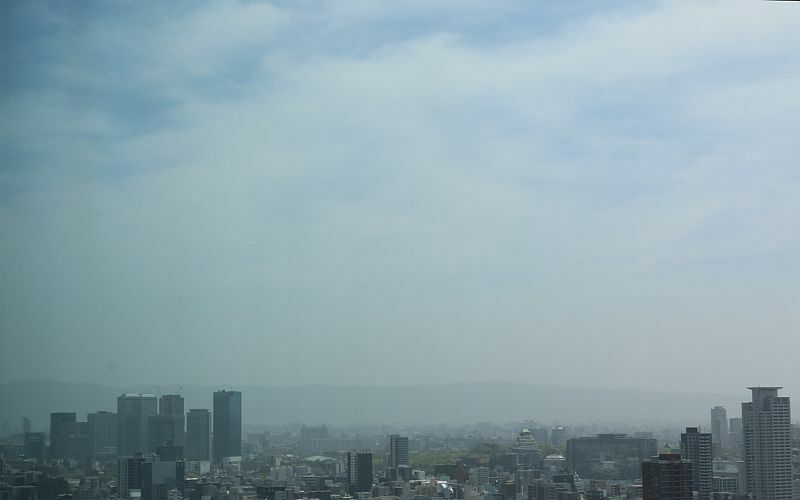 [写真]生駒山方面を望むと青空が少しみえるが、生駒山などがほとんどかすんでいる。中央右下に大阪城=8日午前、大阪市北区から撮影