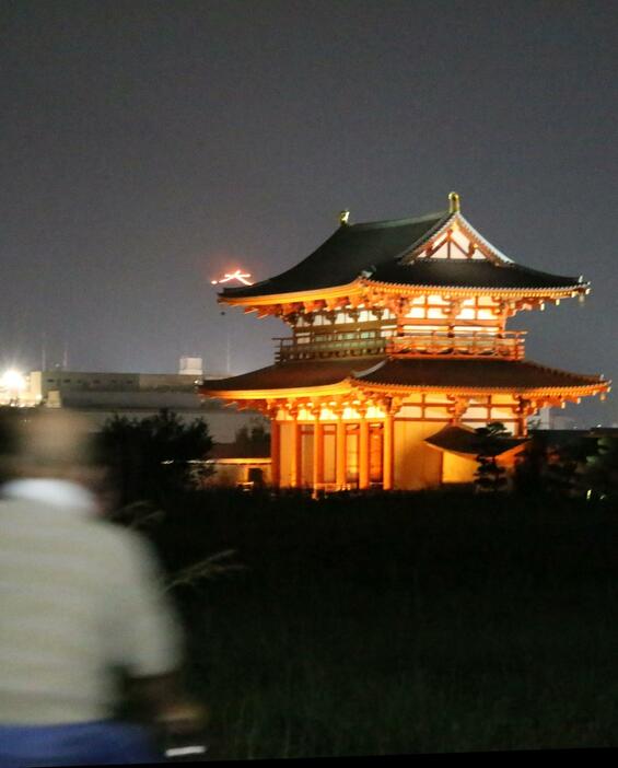 ［写真］平城宮跡へ散歩に来ていた人も、奈良大文字送り火に気づき写真撮影を行う姿もみられた＝15日午後8時半ごろ、奈良県奈良市で