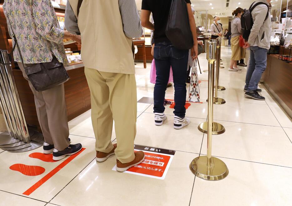 レジ前では他の買い物客との距離を確保するよう床に注意書きがある（写真：つのだよしお/アフロ）