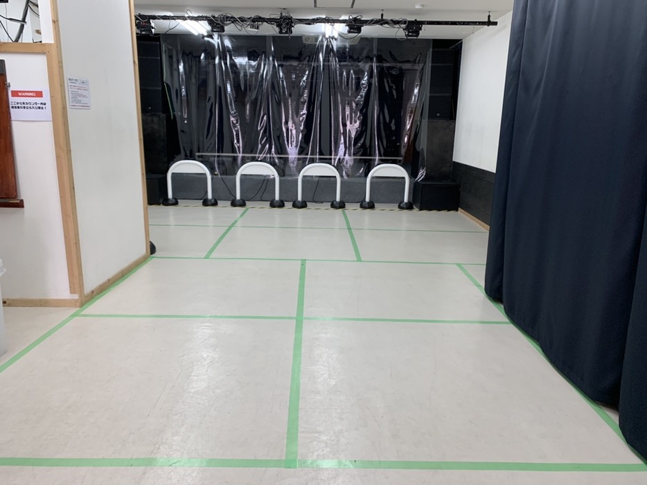 TEATRO西金沢の内部。ステージとフロアの間は、透明のビニールシートで仕切られている。床は、テープで1.5メートル四方に仕切られ、この中でファンは楽しむ（写真：ニシカネプロジェクト）