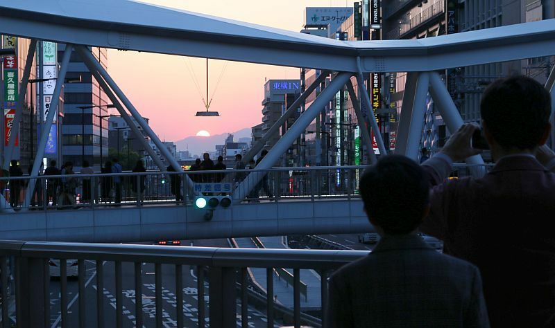 [写真]あべのハルカス前の歩道橋。「夕陽落ちるわ～」と言いながらあわててシャッターを切る人も。歩道橋は自然と夕陽スポットに=28日午後6時40分ごろ、大阪市阿倍野区で（撮影：柳曽文隆）