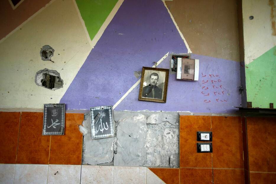 壁に掛けられた写真＝1月30日、シリア北部の街アインアルアラブ、クルド名コバニ（ロイター/アフロ）