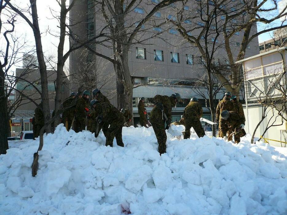 [写真]除雪を手伝う自衛隊員＝12日午前、札幌市内