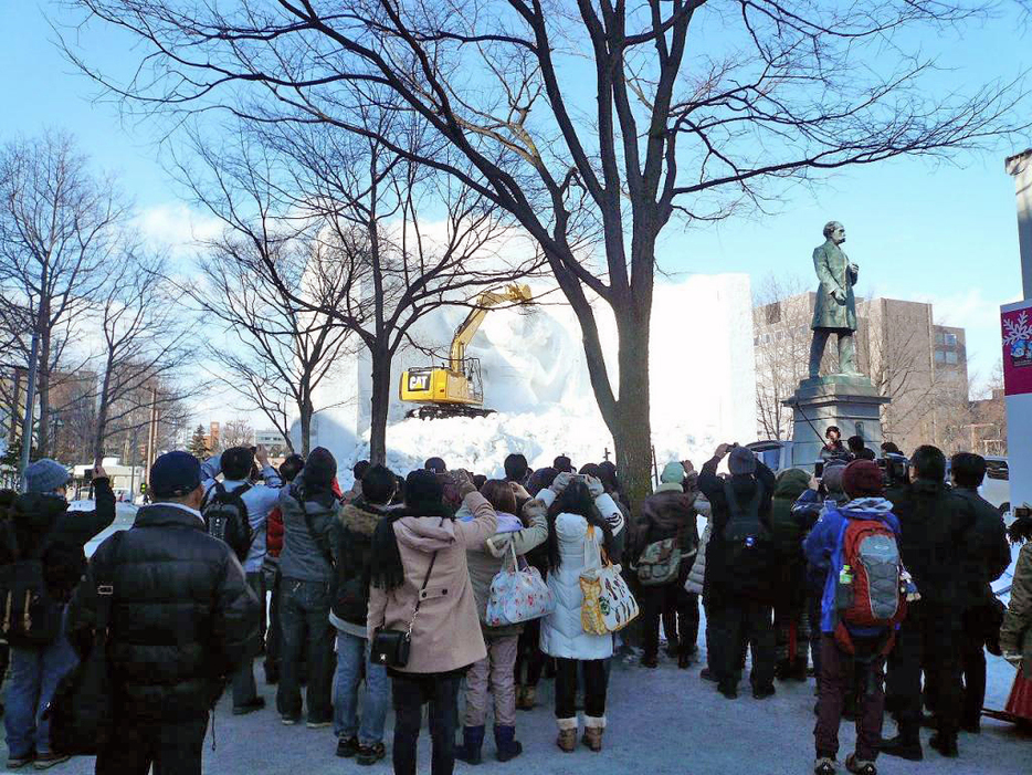 [写真]雪像の解体を見守る観光客ら＝12日午前、札幌市内
