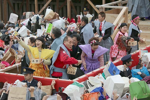 [写真]おけいはん、宮川大助・花子ら。参拝客らは紙袋をめいいっぱい広げている＝3日午前11時ごろ、大阪府寝屋川市で