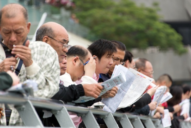 [写真]新聞と鉛筆を持ち、真剣にどの馬に賭けるかを考える人々(撮影、石橋崇司)