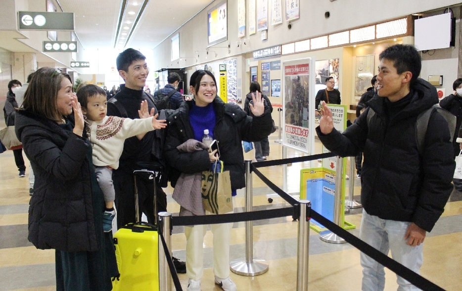 手を振って別れを惜しむ家族＝4日、国東市の大分空港