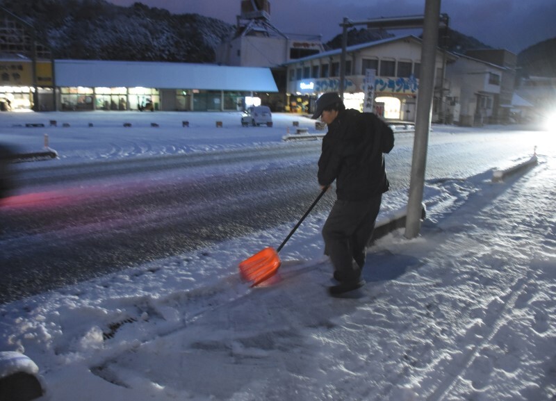 早朝から自宅前の雪かきに追われる住民＝10日午前6時40分、真庭市勝山