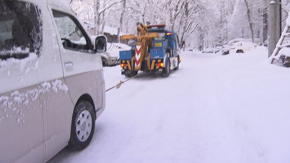 坂道を登れなくなった車をロープをつないで引き上げる