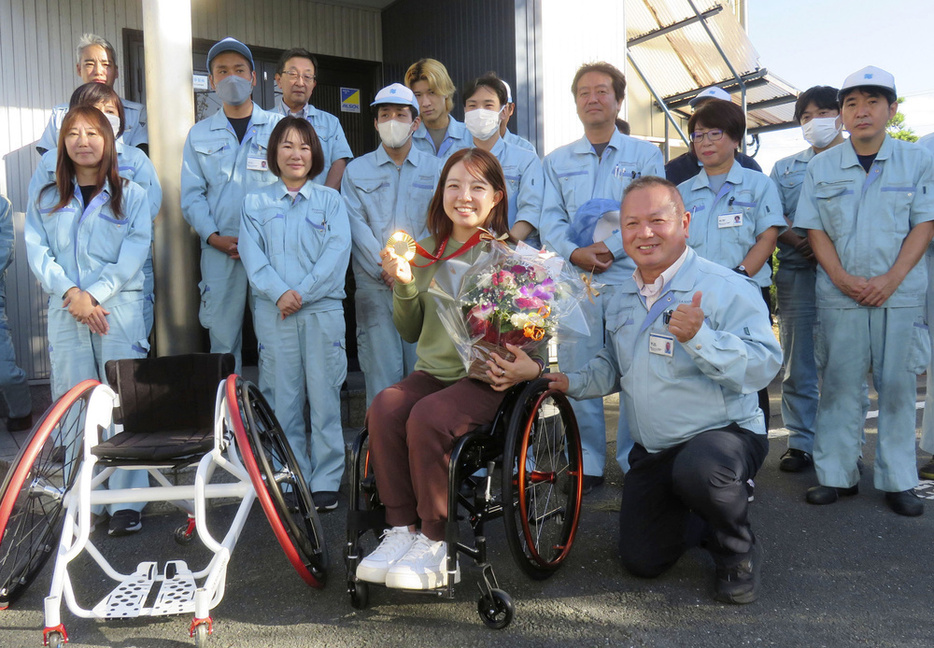 パリ・パラリンピック車いすテニス金メダリストの田中愛美選手（中央）と笑顔でポーズをとる橋本エンジニアリングの橋本裕司社長（手前右）ら＝浜松市（同社提供）