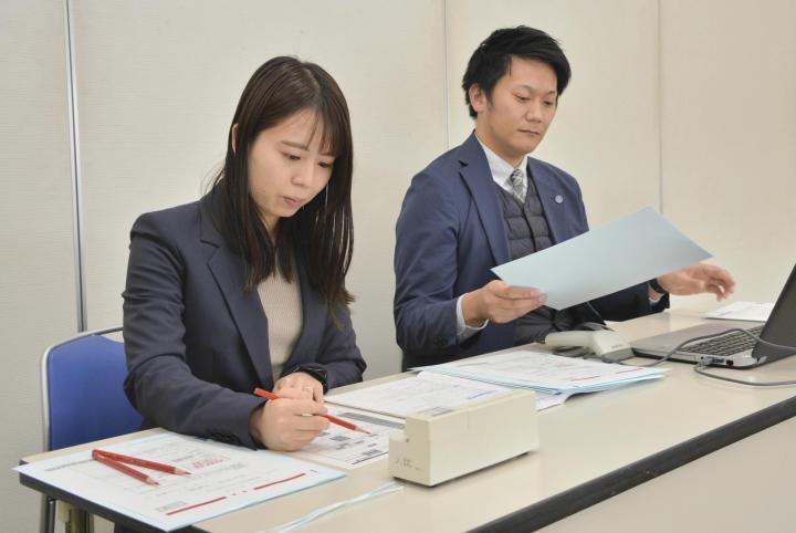 見本を使って願書の確認手順をチェックする松山大職員＝6日午後、松山市文京町