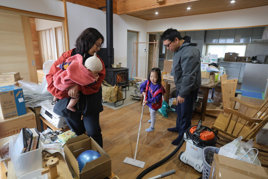 津波を受けた室内の掃除や片付けをする藤部巴さん（左奥）と夫の裕太さん（右）。中央は長女ふみちゃん。左手前は抱えられる長男麦ちゃん＝２０２４年１２月８日、石川県珠洲市