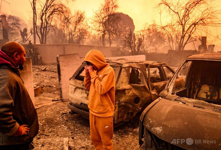 カリフォルニア州ロサンゼルス郡アルタデナで、焼けた自宅の前で涙する住民（2025年1月8日撮影）。【翻訳編集】 AFPBB News