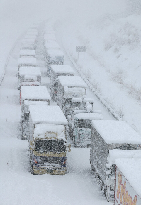 降雪の中、新名神高速道路で立ち往生する大型車両＝三重県菰野町で2023年1月25日午後2時6分、兵藤公治撮影