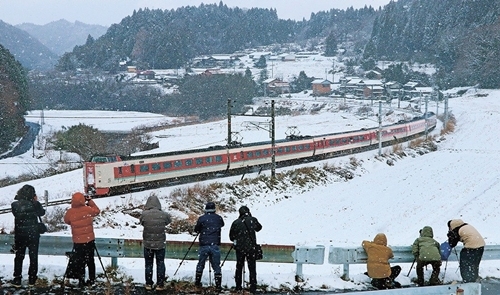 雪景色の中国山地を駆け抜ける３８１系特急やくもを撮影する鉄道ファン＝鳥取県日南町下石見