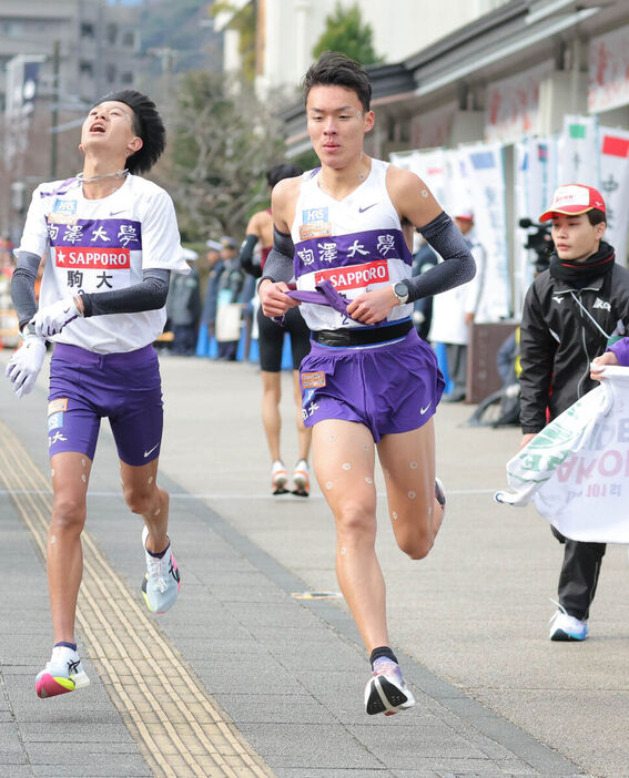 タスキを受け取る７区の駒大・佐藤（カメラ・中島　傑）