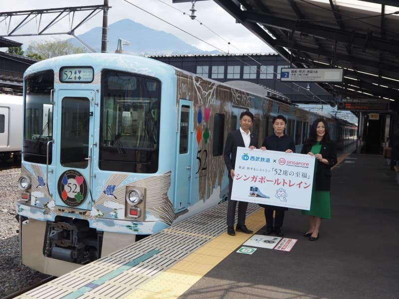 「西武　旅するレストラン『５２席の至福』」に向かって横断幕を掲げ、手を振る西武鉄道小手指乗務所の乗務員ら＝２０２４年８月２１日、埼玉県所沢市