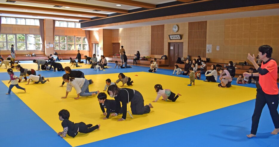 中村さん（右）のアドバイスを受けながら運動する親子＝福知山市猪崎・市武道館