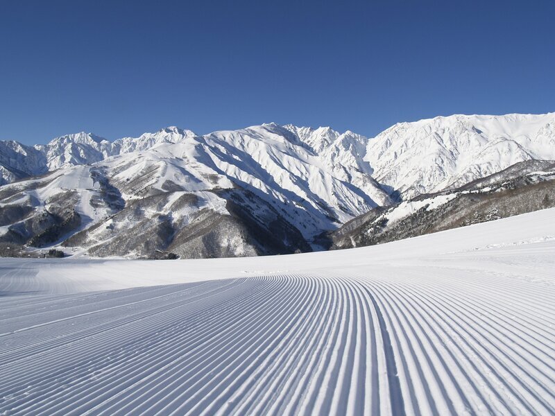 早朝の圧雪斜面の気持ちよさを山々が引き上げる