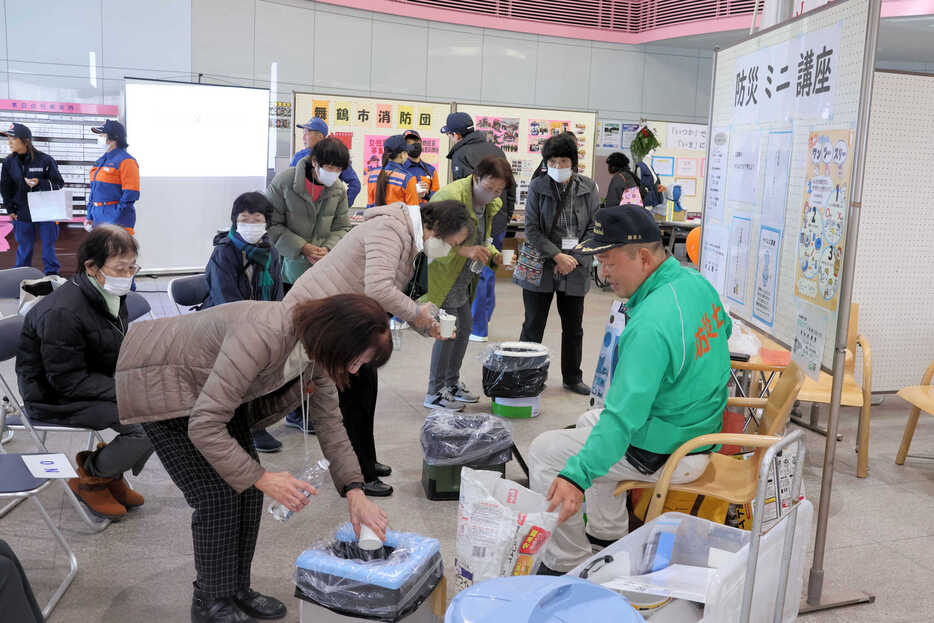 防災士の田上さん（右）の講座で、簡易トイレを試す来場者＝京都府舞鶴市・中総合会館