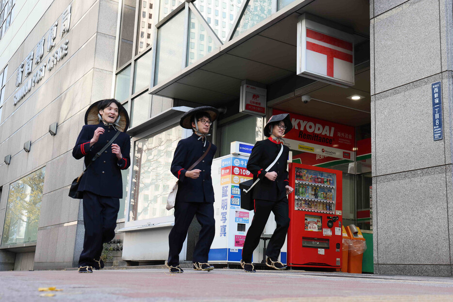 創業時などの制服姿で年賀状配達に出発する郵便局員ら＝１日午前、東京都新宿区