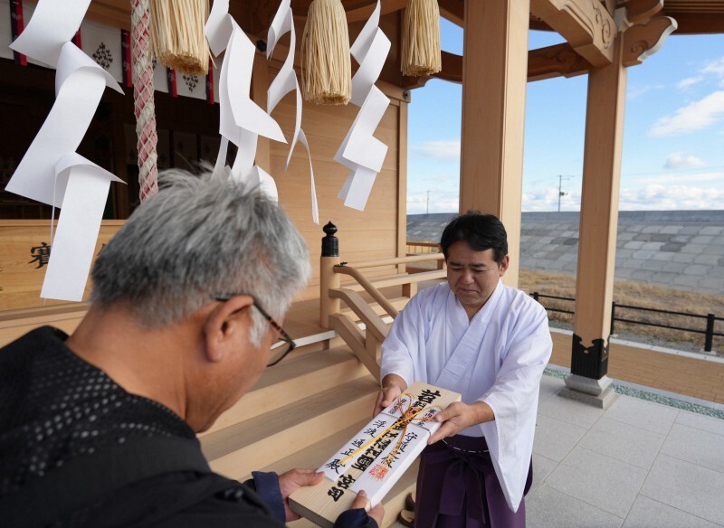 14年ぶりに新年のお札を田村貴正宮司（右）から受け取る参拝者＝浪江町請戸の苕野（くさの）神社で2025年1月2日、尾崎修二撮影