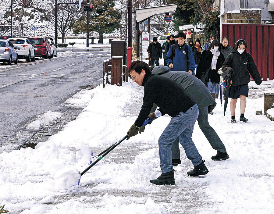 夜間に積もった雪をよける人＝１０日午前７時５５分、金沢市本多町３丁目