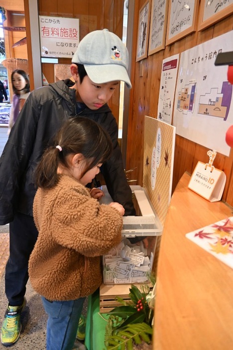 虫みくじを引く来場者＝磐田市大中瀬の竜洋昆虫自然観察公園