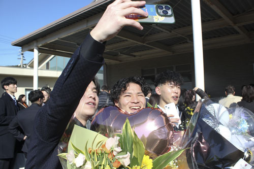 【式典後に旧友との写真撮影を楽しむ出席者ら＝熊野市井戸町の市文化交流センターで】