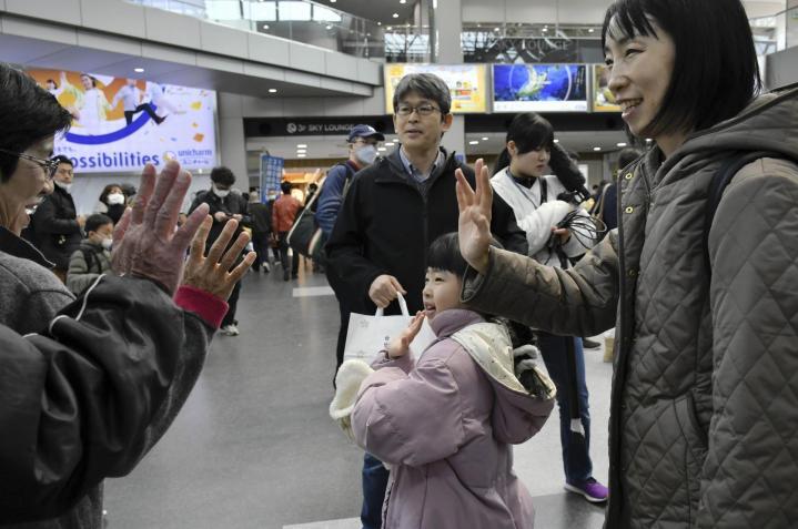 見送りに来た家族に手を振り、出発ロビーを後にする帰省客＝4日午前、松山市南吉田町