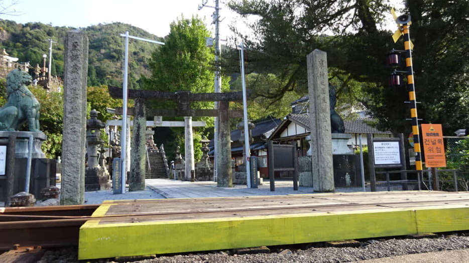 石段を上がってきた側から撮影するとこんな視界に。陶山神社参道に堂々と設置されている線路。遮断機は見当たらない。この目の前を特急が走るとかなり恐ろしそうだ。鳥居脇の狛犬は青銅製としては日本一の大きさを誇るのだという。こちらも必見だ。撮影：森田季節