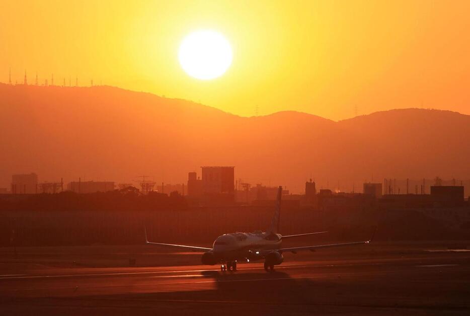 生駒山から昇る太陽を背にＢ滑走路を走る飛行機＝１日午前７時１７分、伊丹市森本７、伊丹スカイパーク