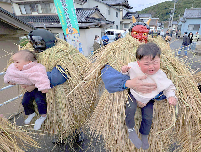 子どもを抱き上げ、怠け心を戒めるアマハゲ＝遊佐町吹浦