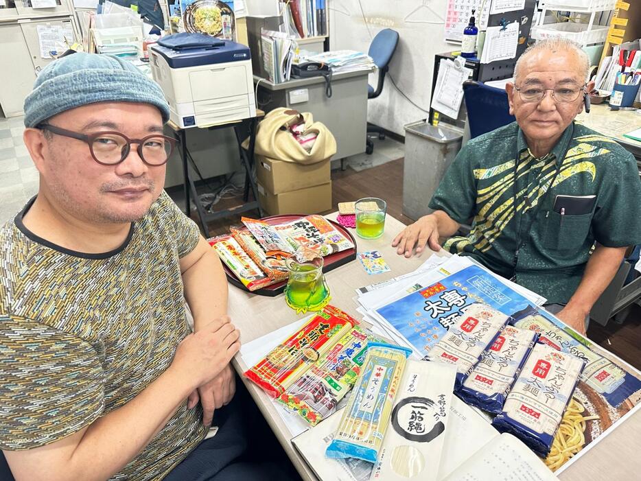 ソーメンチャンプルーを追い沖縄に通うソーメン二郎さん（左）。右はマルタケ食品の金城武則社長＝2024年9月、糸満市西崎町