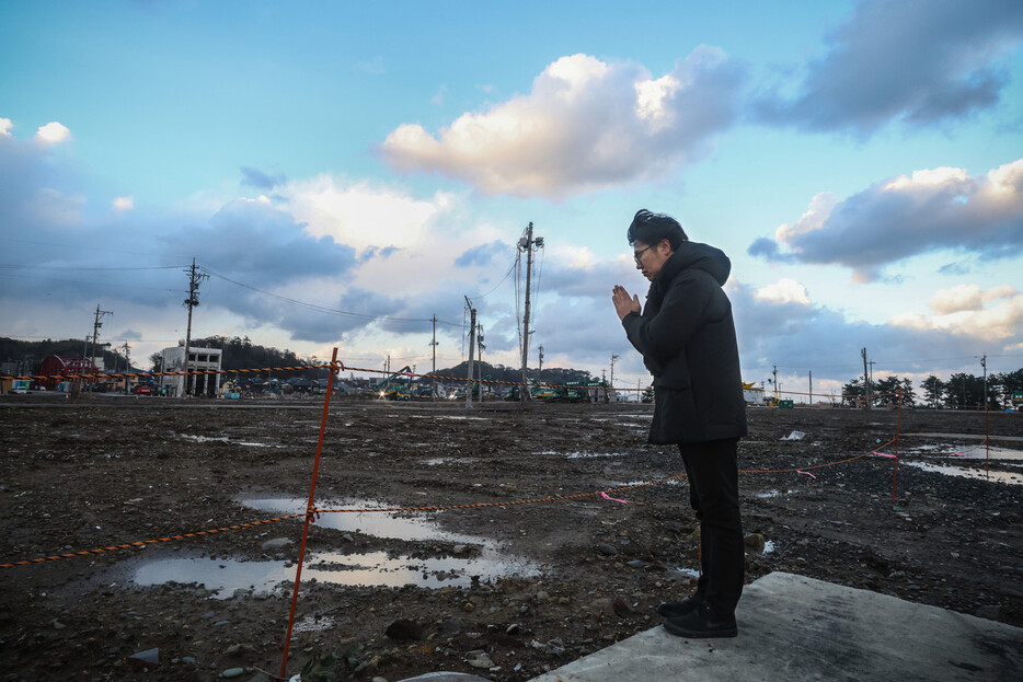 大規模火災で焼けた建物の解体が進む石川県輪島市の観光名所「朝市通り」近くに住む二俣大輔さん（４８）。犠牲者に手を合わせると、「子どもの頃によく遊んだ思い出の場所。地震が先月だったみたいに、あっという間に過ぎた１年だった」と振り返った＝３１日午後