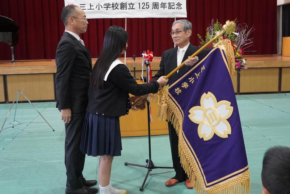 市木委員長から児童代表の中岡さんに校旗が贈られた