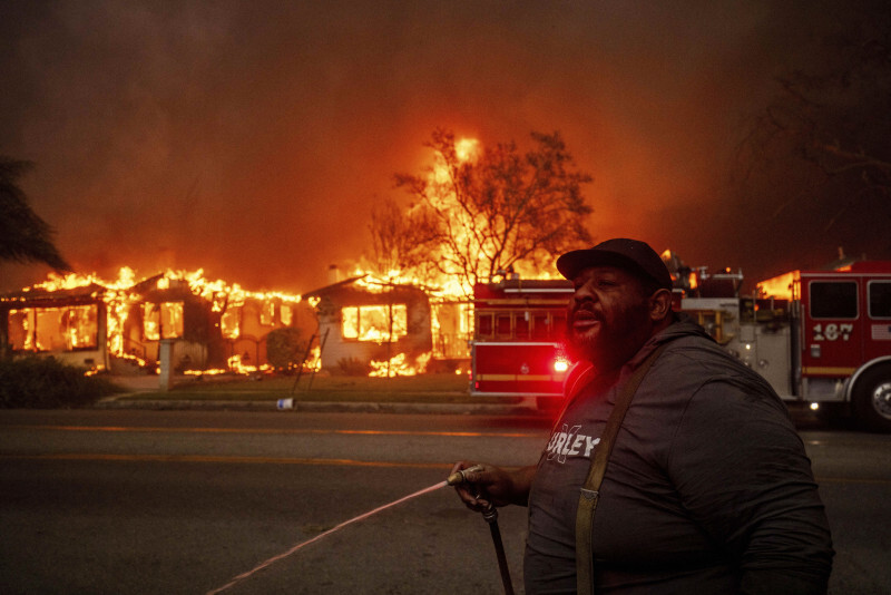 山火事が広がる住宅街でホースで放水する住民＝米西部ロサンゼルス近郊で2025年1月8日、AP