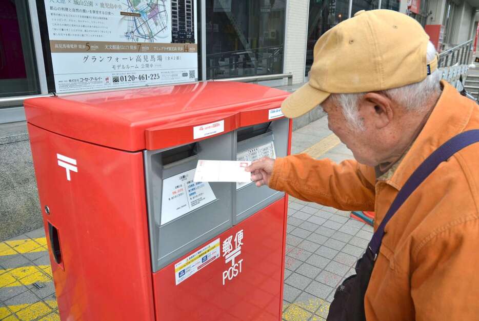 年賀状のお礼のはがきを投函する男性＝８日、鹿児島市の鹿児島中央郵便局