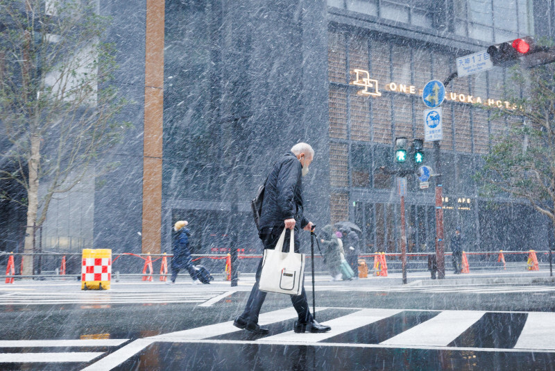 雪が強く降る中、つえをついて横断歩道を渡る男性＝福岡市中央区で2025年1月9日午前10時52分、吉田航太撮影