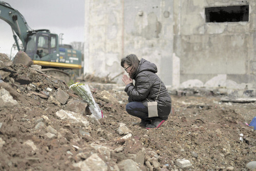 能登半島地震から１年、亡くなった親族の自宅跡で冥福（めいふく）を祈る女性（１日、輪島市の朝市通りで）＝関口寛人撮影