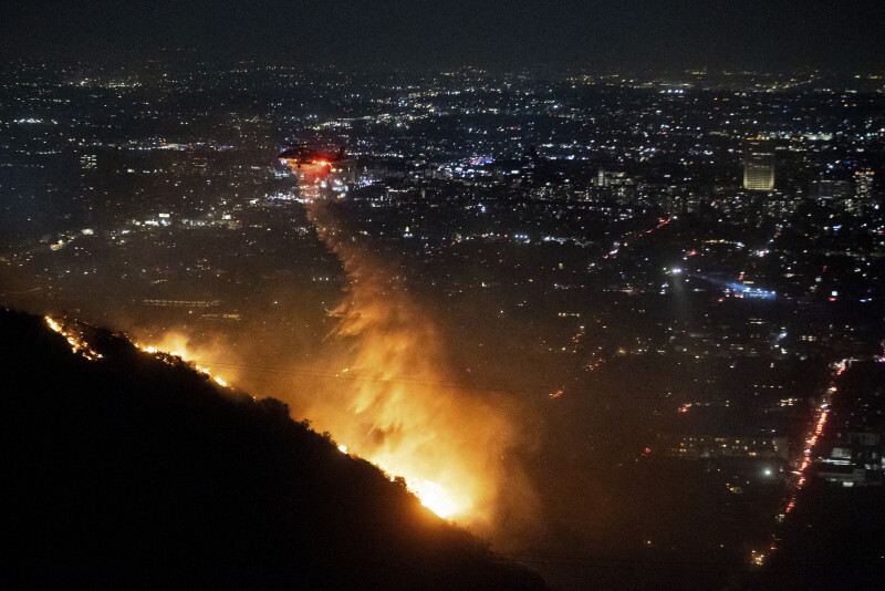 米西部カリフォルニア州ロサンゼルスで、ハリウッドヒルズの山火事の消火活動にあたるヘリコプター＝2025年1月8日、AP