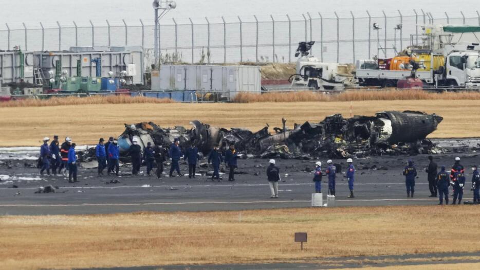 日航機と衝突し、焼け焦げた海上保安庁の航空機の周辺に集まる警視庁の捜査員や東京消防庁の隊員ら＝2024年1月3日、羽田空港