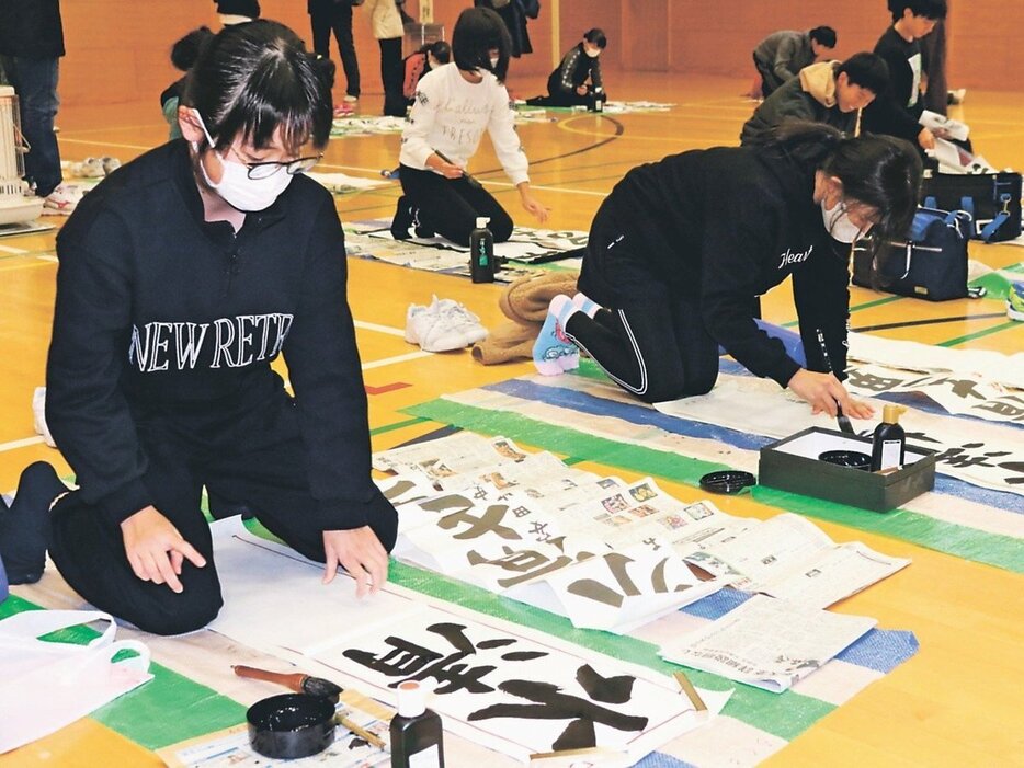 力強い筆運びで書き上げる参加者＝高岡市伏木小学校