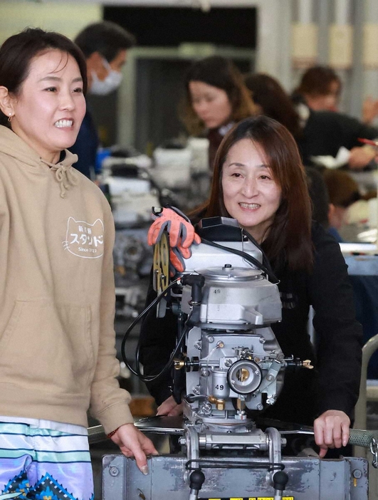 香川素子（左）と談笑しながらエンジンを運ぶ水口由紀