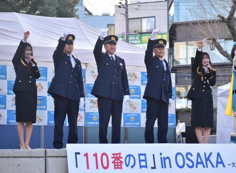 「110番の日」のイベントに登場したNMB48の塩月希依音さん（左端）、青原和花さん（右端）、大阪府警本部の田畑修治地域部長（中央）ら＝枚方市のニッペパーク岡東中央で2025年1月10日午後3時1分、斉藤朋恵撮影