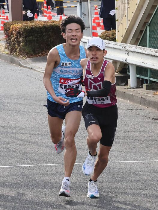 関東学生連合１０区の武蔵野学大・福本陽樹にタスキを渡した９区の東大大学院・古川大晃（左、カメラ・佐々木　清勝）