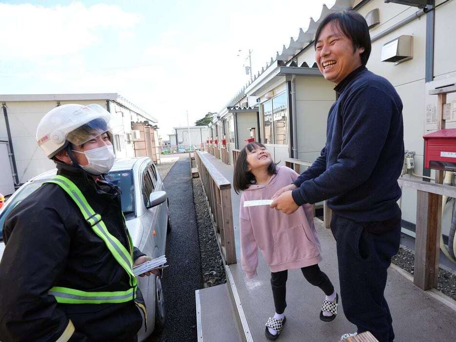 郵便局員から仮設住宅で年賀状を受け取る会社員の吉田直生さんと娘の栄美花さん　＝1日午前、石川県珠洲市（鴨川一也撮影）